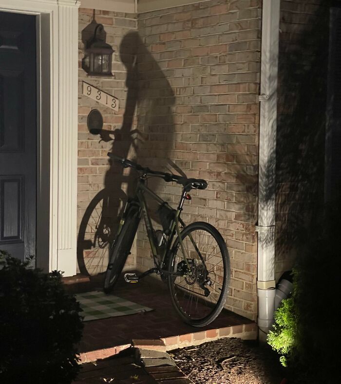 Shadow of a bicycle cast on a brick wall creating a cool and interesting visual effect at night.