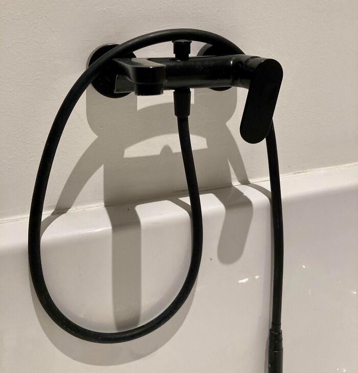 Bathroom faucet and hose casting a cool and interesting shadow that looks like a face, highlighting bizarre shadows effects.