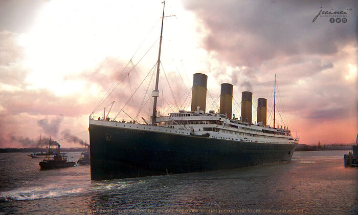 Colorized historical photo of the Titanic ship sailing at sunset with a cloudy sky and smaller boats nearby.