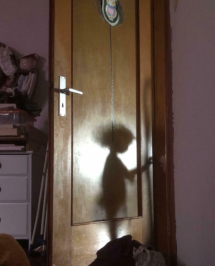 Shadow of a child with an afro hairstyle reaching for a door handle, one of the cool interesting shadows that made people look twice.