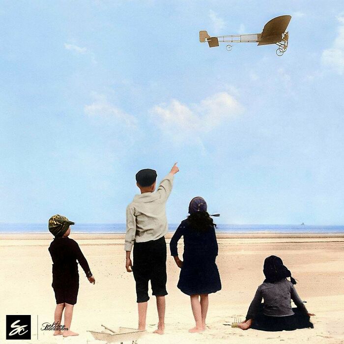 Children on a beach watching an early model airplane in flight in an interesting colorized history pic.