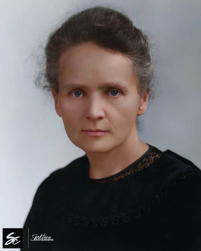Colorized history pic of a woman with blue eyes and curly hair wearing a black dress against a neutral background.