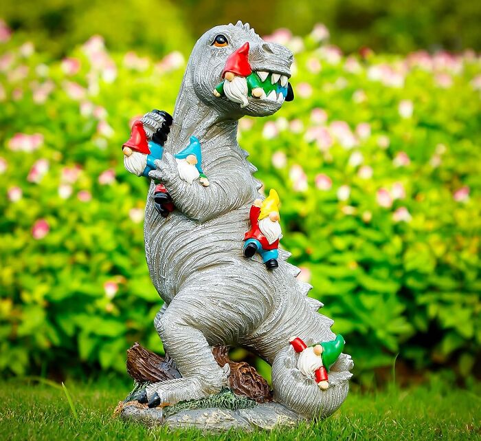 Garden sculpture of a dinosaur covered with colorful gnomes, showcasing one of Amazon's most wished for weirdly wonderful items.