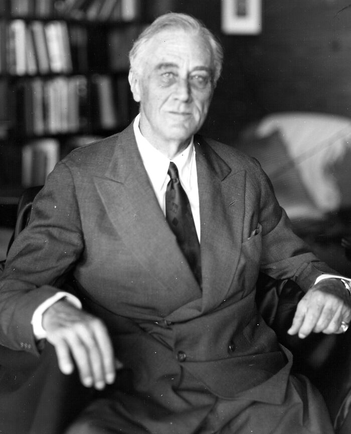 Black and white photo of a famous person seated in a suit, one of the last known photos of these famous people.