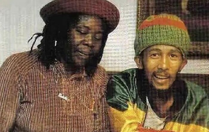 Two famous people sitting together, wearing colorful hats and casual clothing in a candid moment, last known photos.