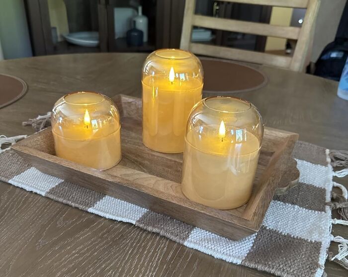 Three yellow candles with glass covers on a wooden tray featured among Amazon's most wished for items.