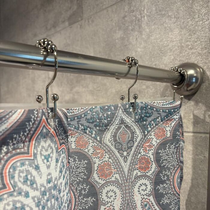 Metal curtain rod with patterned fabric panels hanging on modern hooks, showcasing old inventions with a major glow up.
