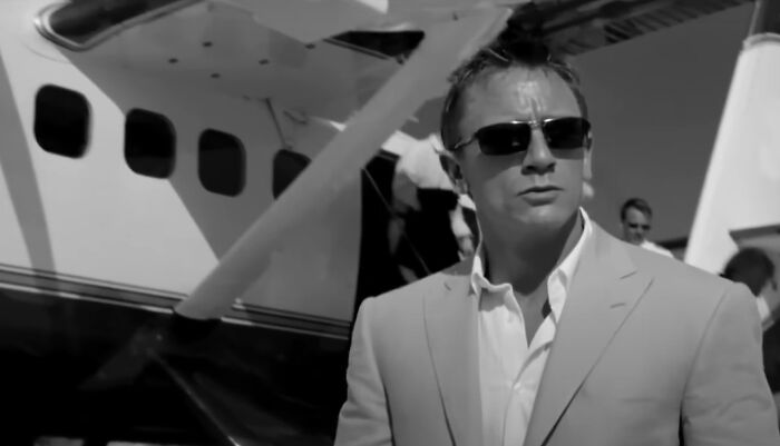 Man wearing sunglasses and a suit standing in front of a small plane, representing new millennium greatest films.