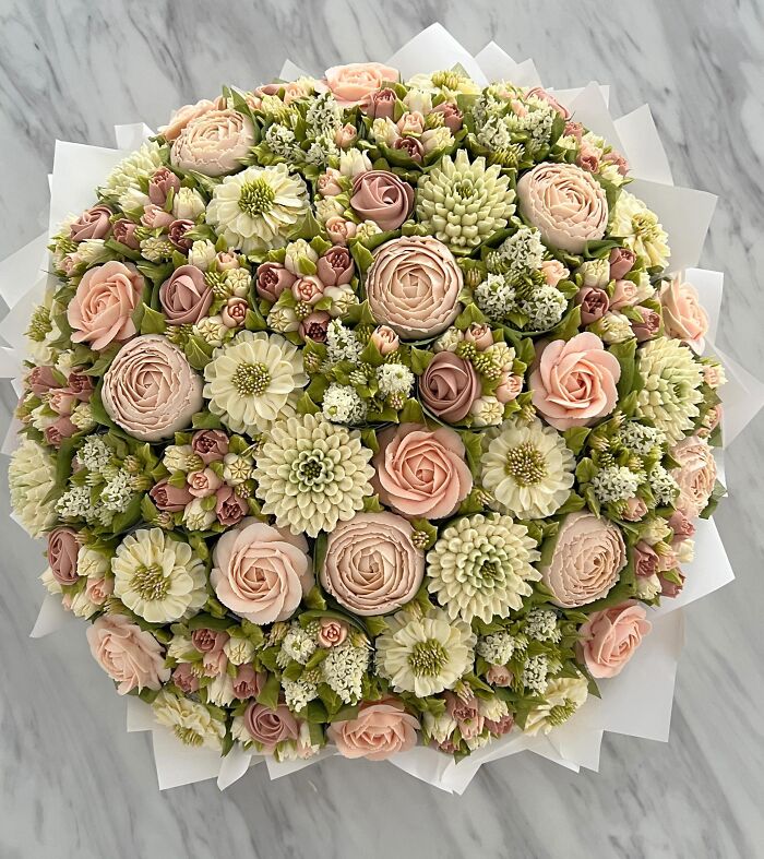 Bouquet of baked goods resembling flowers with detailed frosting, showcasing creative cupcake art by a skilled artist.