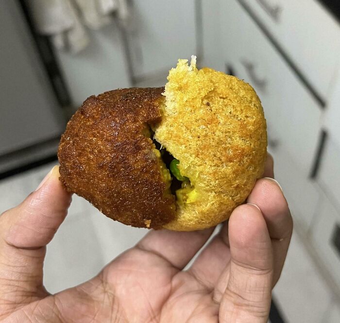 Hand holding a snack with contrasting golden and dark brown fried halves, showcasing variety in comparison pics.