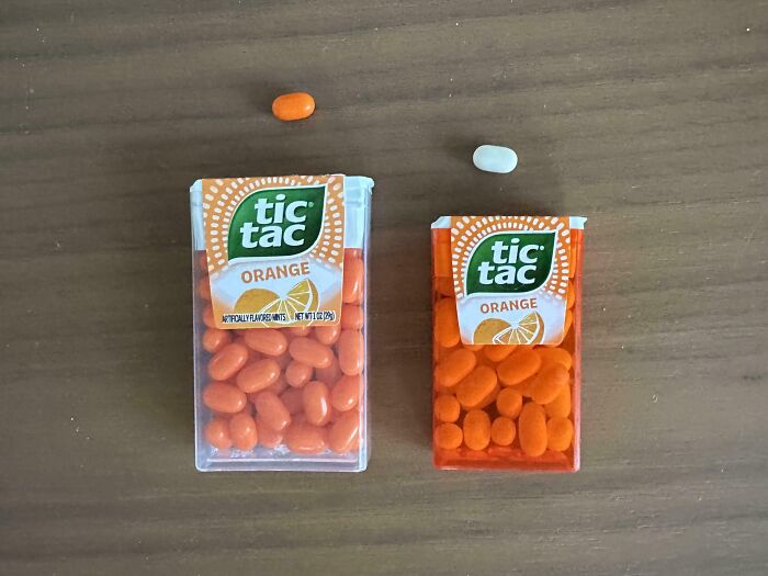 Comparison pics showing two different sizes of orange Tic Tac containers and candies on a wooden surface.