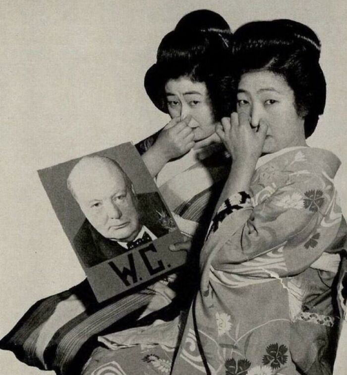 Two women in traditional clothing holding a humorous sign, representing fascinating content with amazing and interesting facts.