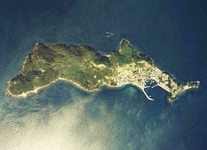 Aerial view of a small island surrounded by clear ocean waters, showcasing fascinating and interesting natural features.