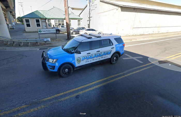 Police SUV parked at an intersection captured on Google Maps, showcasing unusual street shenanigans and urban scenes.