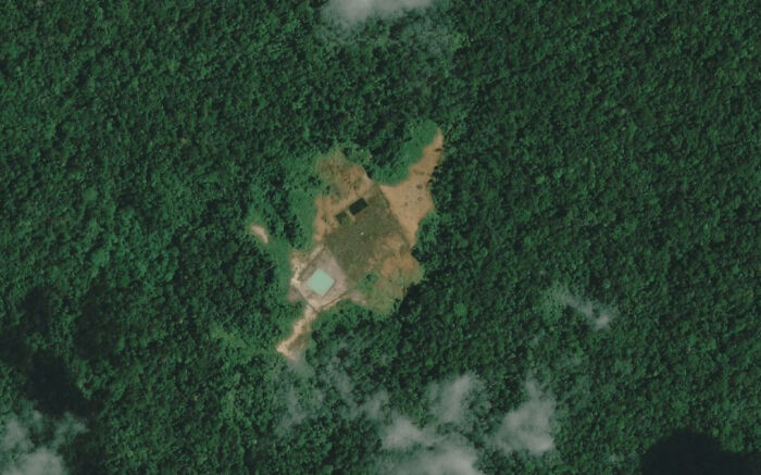 Aerial view of an unusual clearing in dense forest captured on Google Maps showing unexpected shenanigans from above.