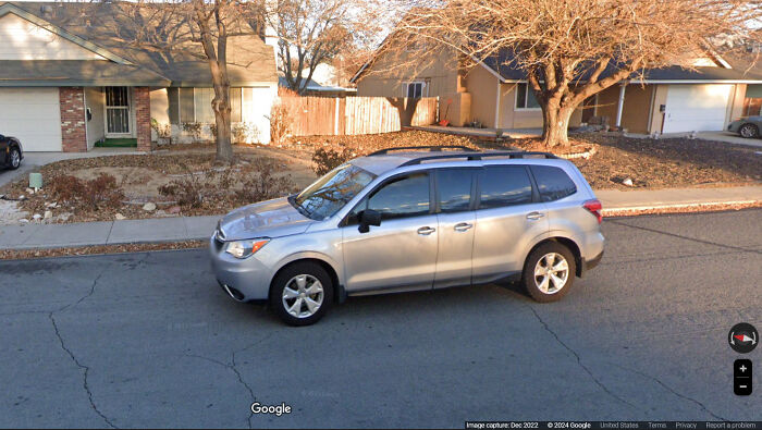 Silver SUV parked on a suburban street with dry trees and houses, a shenanigans moment captured on Google Maps.
