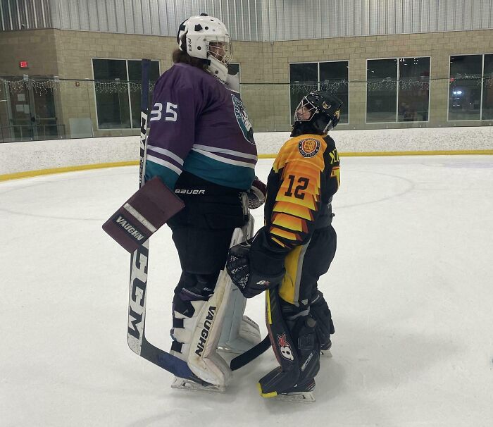 Comparison pic of two ice hockey players with notable height difference on an indoor rink showing variety in sports.