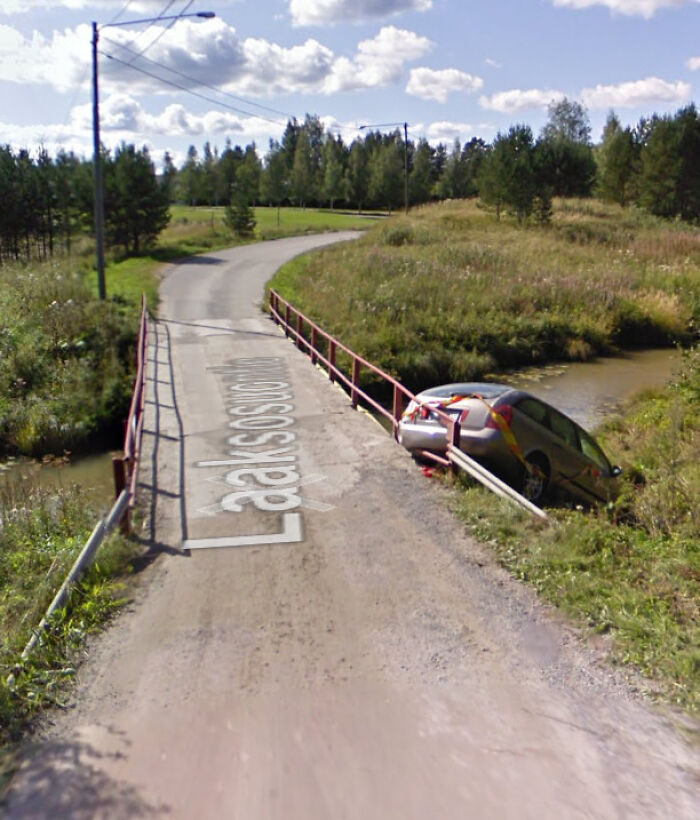 Car stuck off narrow rural bridge captured on Google Maps showing unusual shenanigans on the road.