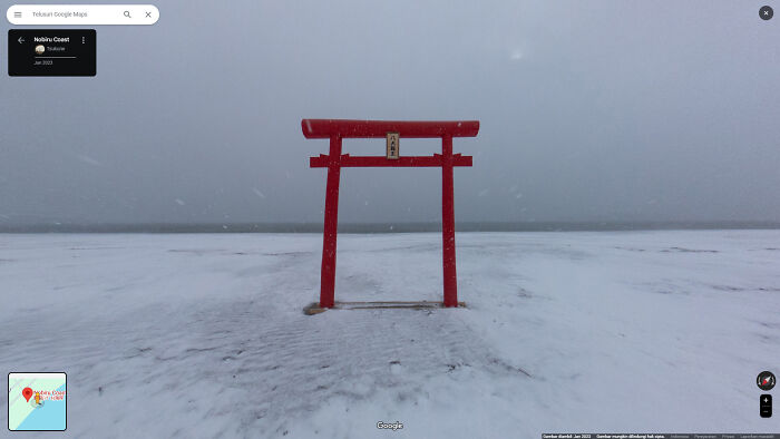 Red torii gate standing alone on a snowy beach, an unusual shenanigan captured on Google Maps.