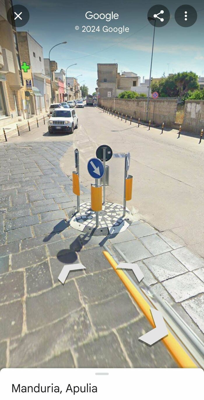Traffic signs crowded on a small traffic island in street corner captured on Google Maps showing unusual street shenanigans.