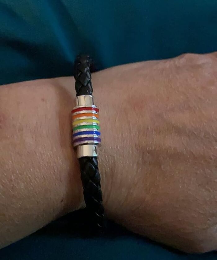 Black braided bracelet with a silver charm featuring colorful rainbow stripes for pride pieces style accessory