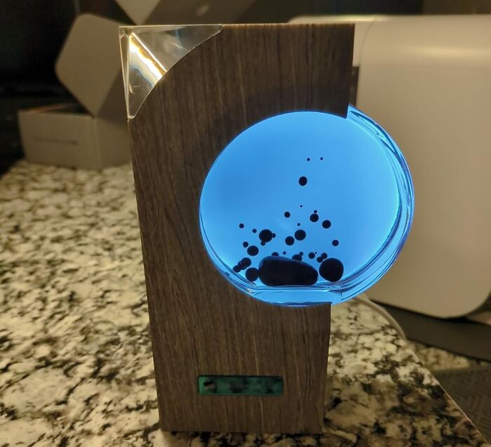 Wooden desk accessory with glowing blue liquid and floating black bubbles to brighten up a 9-to-5 workspace.