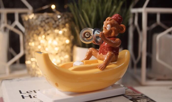 Monkey toy playing cymbals in a yellow boat, a fun desk accessory to make the 9-to-5 less blah workspace more lively.
