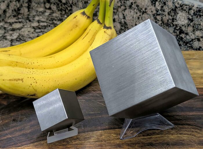 Two metal cubes of different sizes compared next to bananas, illustrating fascinating comparison pics and the variety of life.