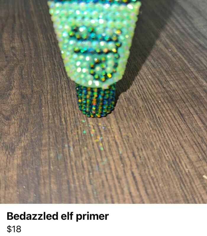 Bedazzled craft project of elf primer covered in small colorful rhinestones on a wooden surface.