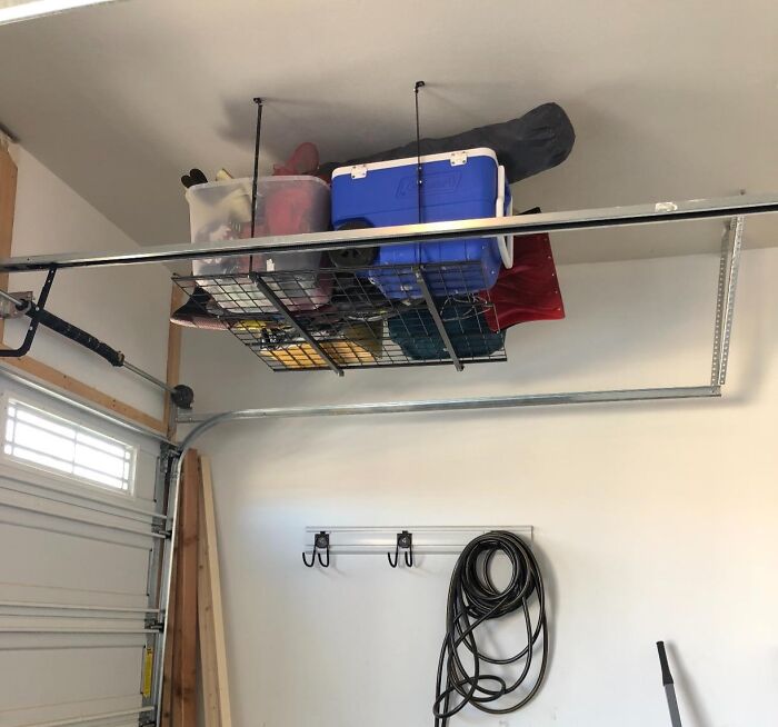 Overhead storage rack in garage holding coolers and bins, a practical solution for hiding home uglies and clutter.
