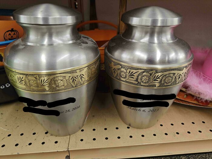 Two metal urns with floral designs and engraved dates found in a thrift store among unusual items.