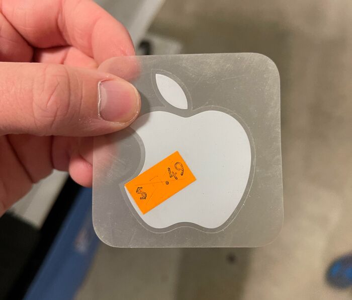 Hand holding a scratched Apple logo sticker with a $5.49 price tag found at a thrift store, ridiculous thrift find.
