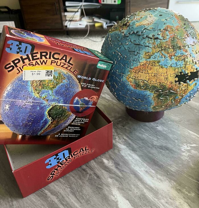 3D spherical jigsaw puzzle of a world globe found at a thrift store with a missing puzzle piece on a stand.