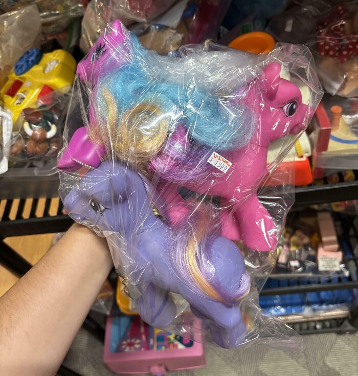 Two vintage My Little Pony toys wrapped in plastic, found at a thrift store among other secondhand items.