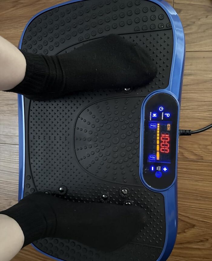 Feet in black socks using a blue vibration plate machine, one of Amazon's most wished for wellness and fitness items.