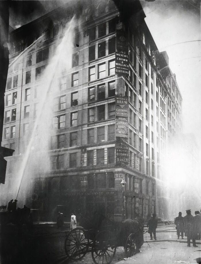 Historic building fire being extinguished by firefighters, illustrating lesser-known historical events captured in black and white.