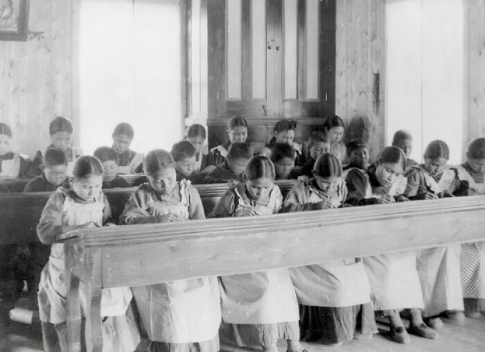 Group of children in a historical classroom setting, highlighting lesser-known historical events and education practices.