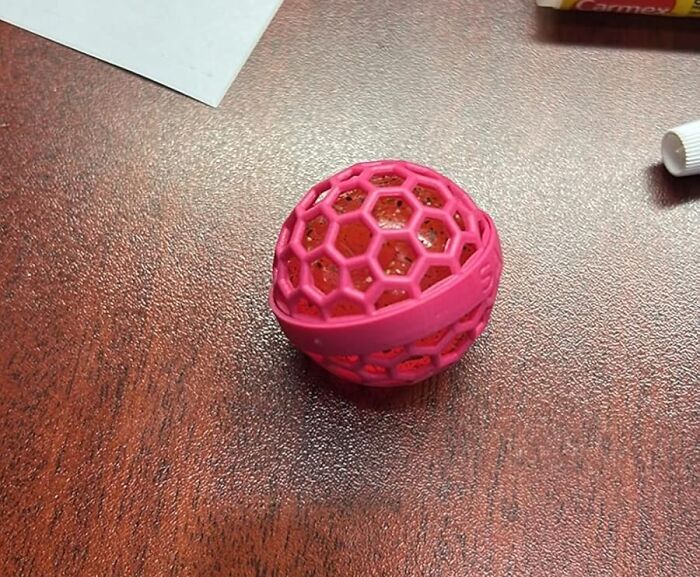 Pink honeycomb-patterned ball-shaped item on a wooden desk, featured among 24 finds as a first executive order.