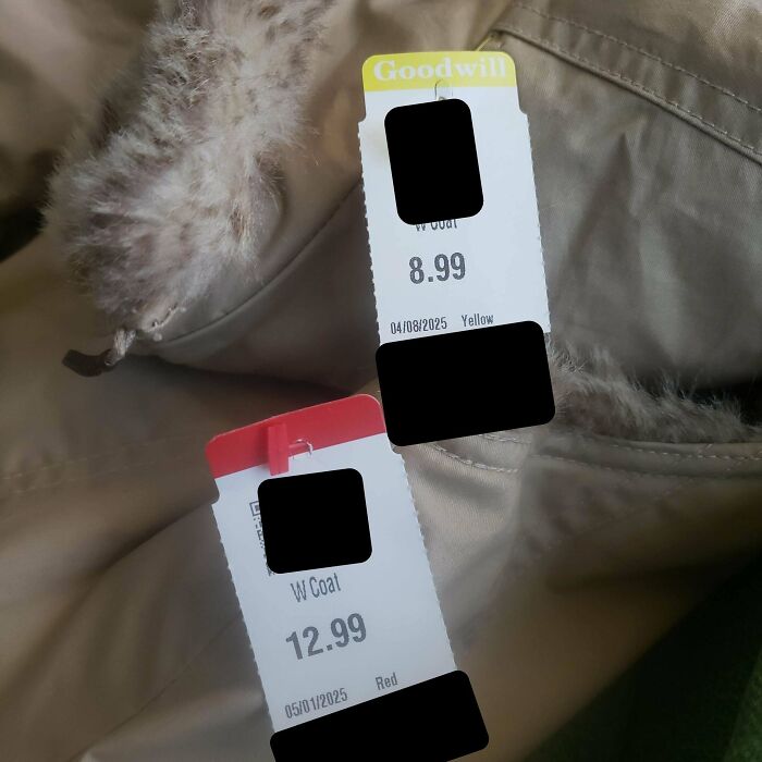 Two thrift store price tags on coats showing different prices on similar items found at Goodwill.