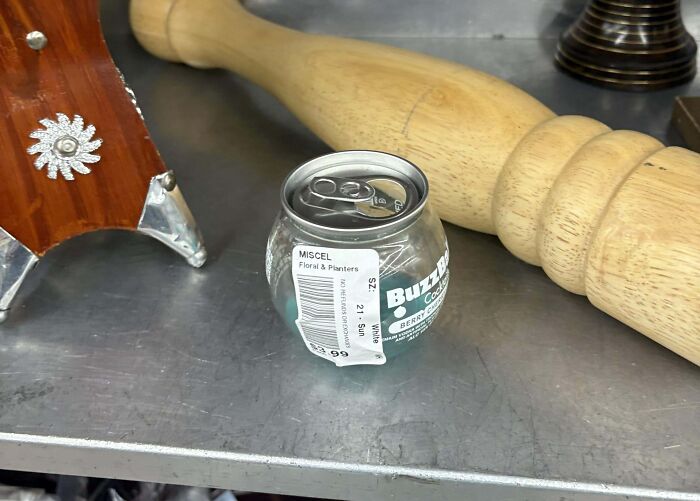 Glass container made from a recycled drink can, found as a ridiculous thrift store item on a metal shelf.