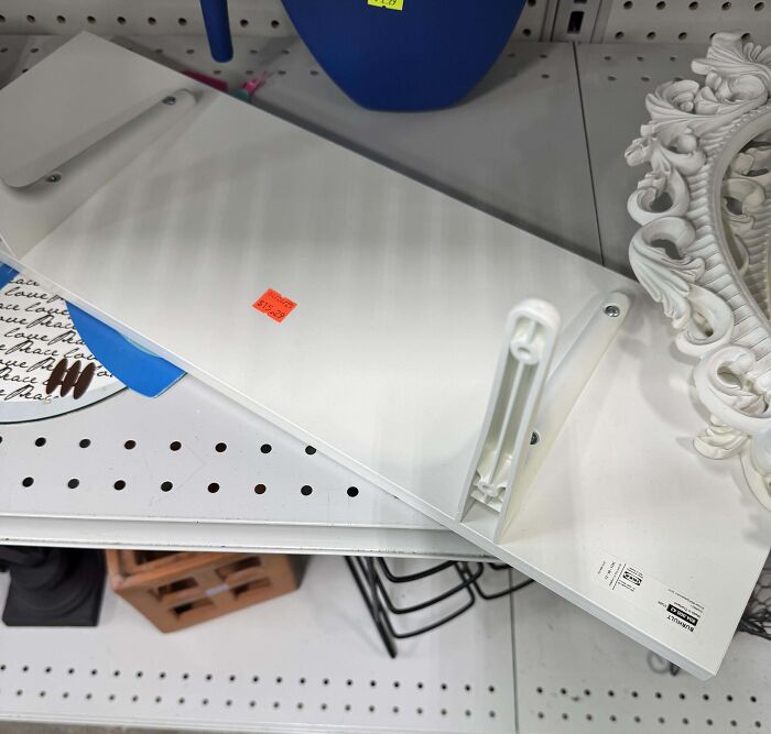 Ridiculous thrift store item, a white plastic board with a price tag, displayed on a store shelf with other miscellaneous items.
