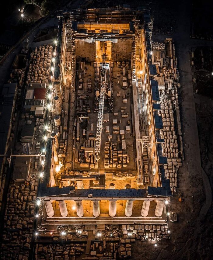 Aerial view of a famous landmark under restoration, showcasing architectural details and construction elements at night.