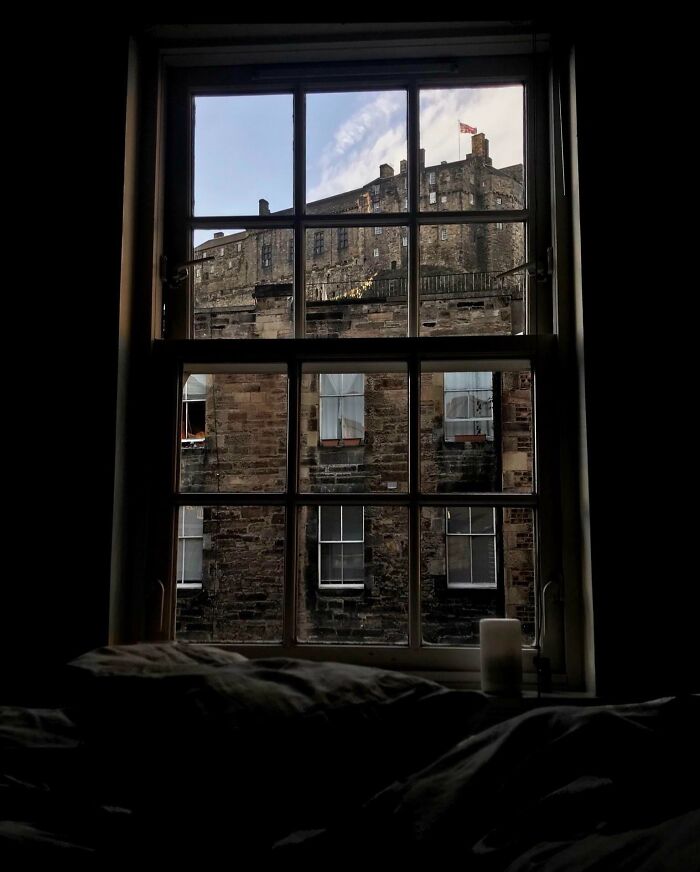 View of a famous landmark through a multi-pane window, showing stone walls and architectural details from an unexpected angle.