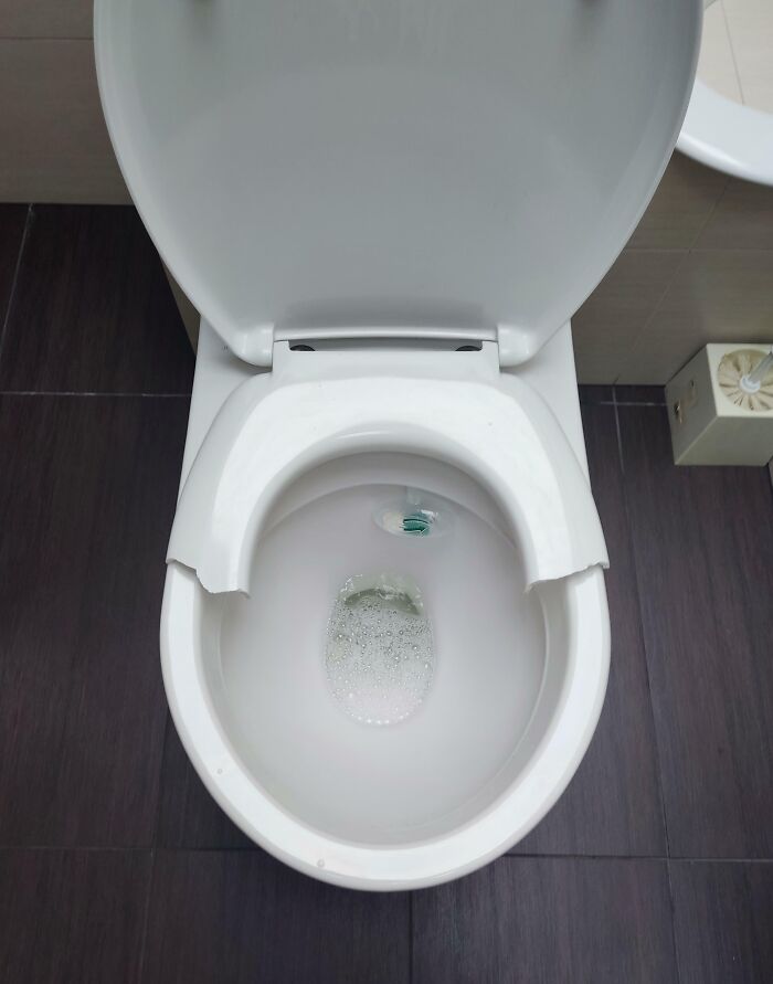 Broken toilet bowl with missing front piece in an extremely toxic work environment restroom, showing poor maintenance and hygiene.