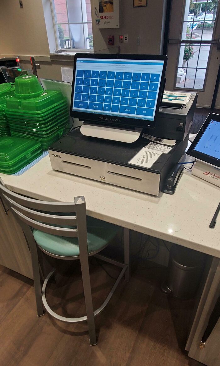 Checkout counter with POS system and stacked green containers in a cramped and cluttered toxic work environment.