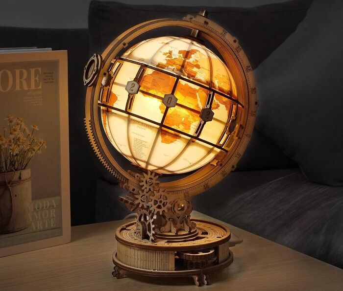 Illuminated wooden globe model kit on table, showcasing intricate gears and craftsmanship for creative crafting projects.