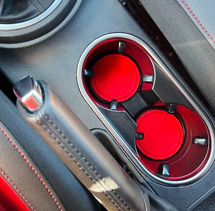 Car interior close-up showing cup holders with red inserts and a black handbrake, clever car finds for the commute.