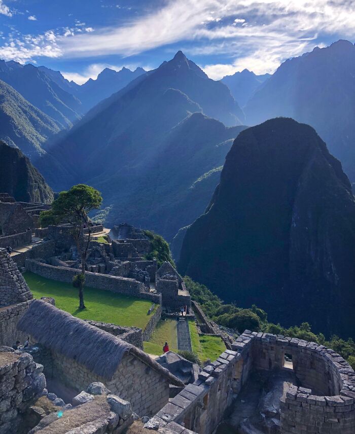 Ancient famous landmarks of Machu Picchu captured from an unexpected angle with mountains and cloudy sky in the background.