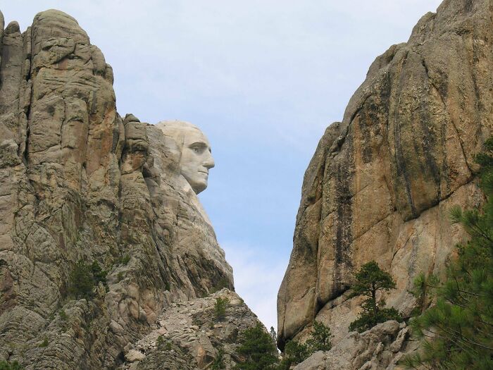 Mount Rushmore seen from an unexpected angle highlighting the famous landmark's profile between large rock formations.