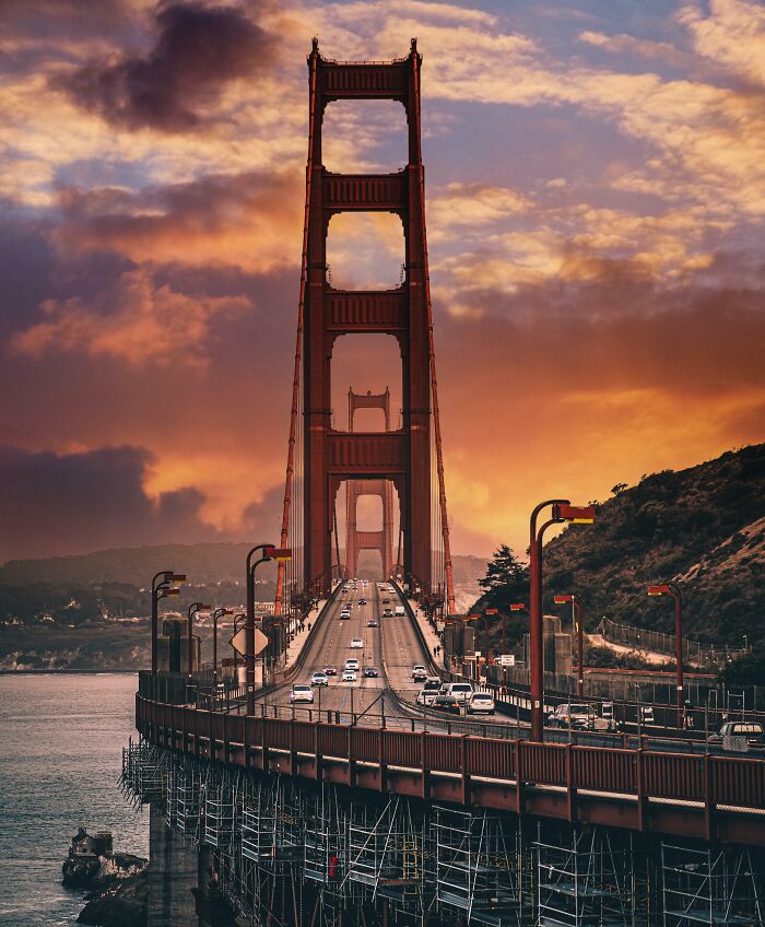 Golden Gate Bridge landmark captured from a unique angle during a dramatic sunset with cars crossing the bridge.